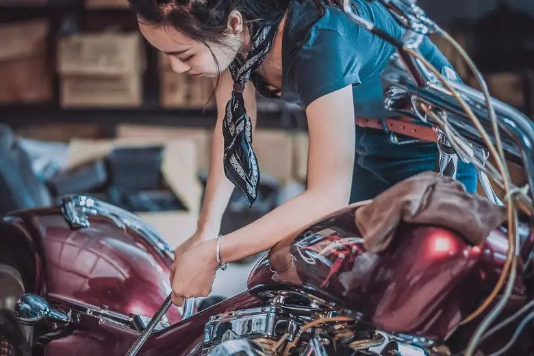 A woman repairing a motorcycle engine
