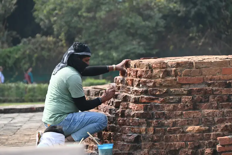 A man rebuilding a brick wall by hand